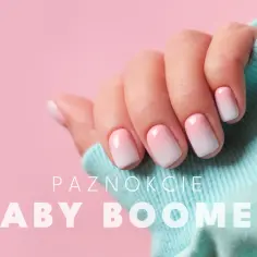 Dłoń z paznokciami w stylu baby boomer, wykonanymi żelem. Delikatny gradient różu i bieli.