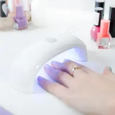 Dłoń z paznokciami w lampie UV. Czy primer wklada się do lampy? Tak, do utwardzenia lakieru hybrydowego.