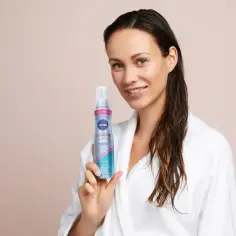 Kobieta w szlafroku trzyma piankę Nivea Diamond. Po zużyciu opakowanie po piance do włosów wyrzuć do plastiku.